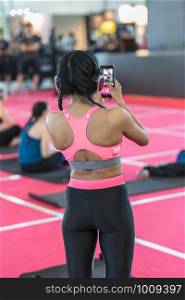 Girls in Fitness Outfit who's Taking a Picture with her Smartphone at a Sporting Event.