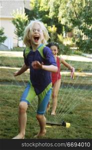 Girls Laughing and Running Through Sprinkler