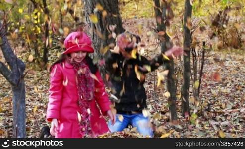 Girls playing in autumn park with leaves