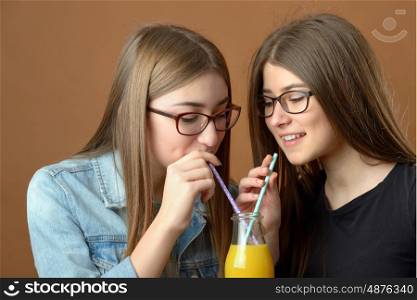 Girls sharing an orange juice drink