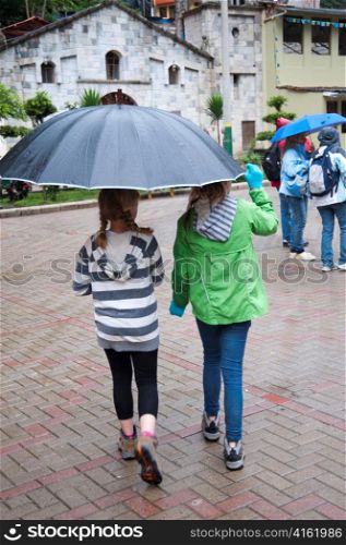 Girls sheltering under an umbrella, Peru