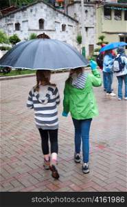 Girls sheltering under an umbrella, Peru