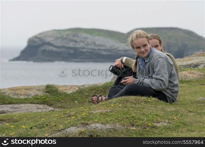 Girls sitting at on the groumd, North Bird Island, Little Catalina, Bonavista Peninsula, Newfoundland And Labrador, Canada