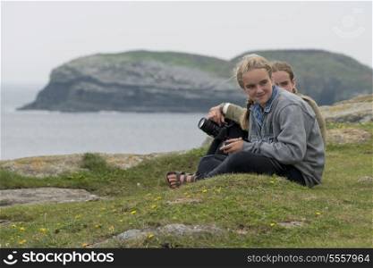 Girls sitting at on the groumd, North Bird Island, Little Catalina, Bonavista Peninsula, Newfoundland And Labrador, Canada