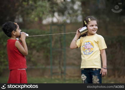 Girls talking through tin can phone