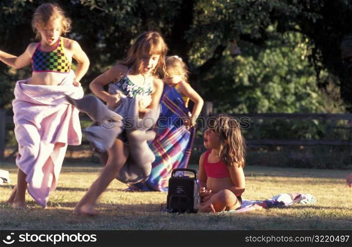 Girls Wearing Swimsuits And Towels And Running In Park