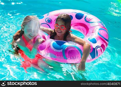 Girls with inflatable ring in swimming pool