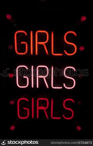 Girls written in neon lights against black background