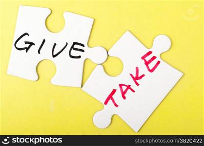 Give and take words written on two pieces of puzzle