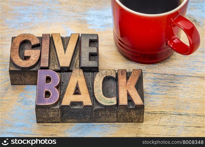 give back word abstract in vintage letterpress wood type printing blocks stained by color inks with a cup of coffee