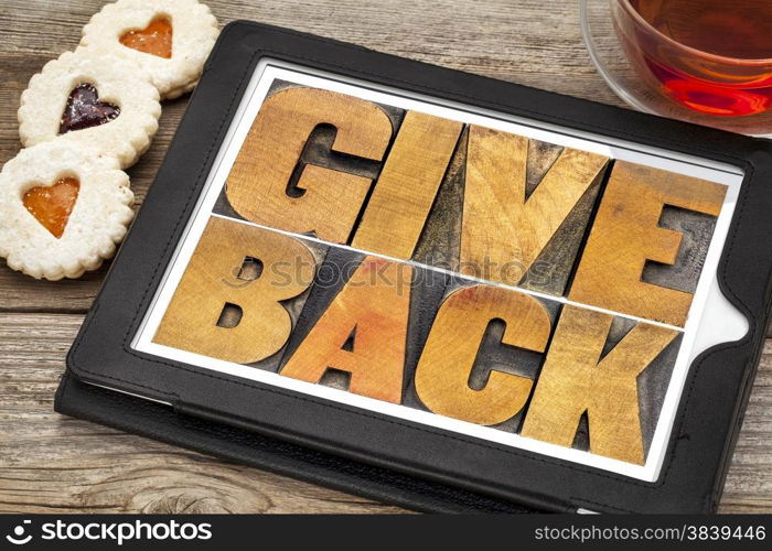 give back words text in letterpress wood type on a digital tablet with tea and heart cookies