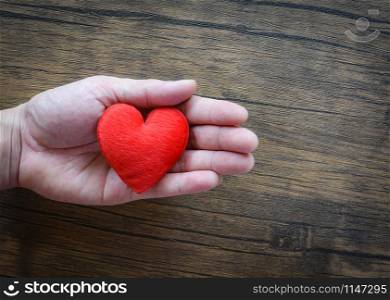 Give Love Man holding red Heart in hands for love Valentines day / Donate Help Give love warmth take care concept on wooden table rustic background