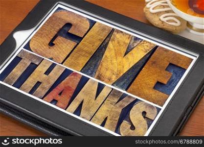 Give thanks - Thanksgiving concept - text in vintage letterpress printing blocks on a digital tablet with cup of tea and cookie