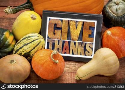 Give thanks word abstract in letterpress wood type on a digital tablet surrounded by pumpkin and winter squash