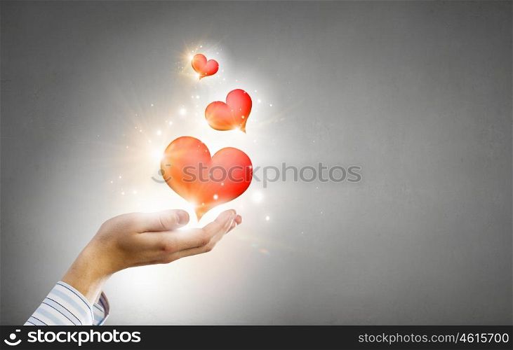 Giving love and care. Close up of hands holding red heart in palms