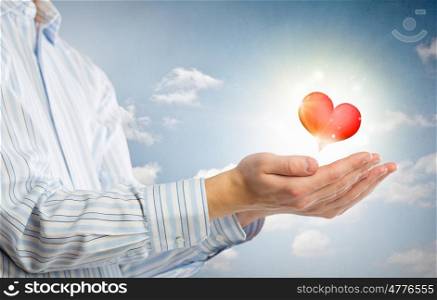 Giving love and care. Close up of hands holding red heart in palms