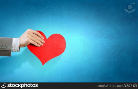 Giving love card. Close up of hands holding red heart