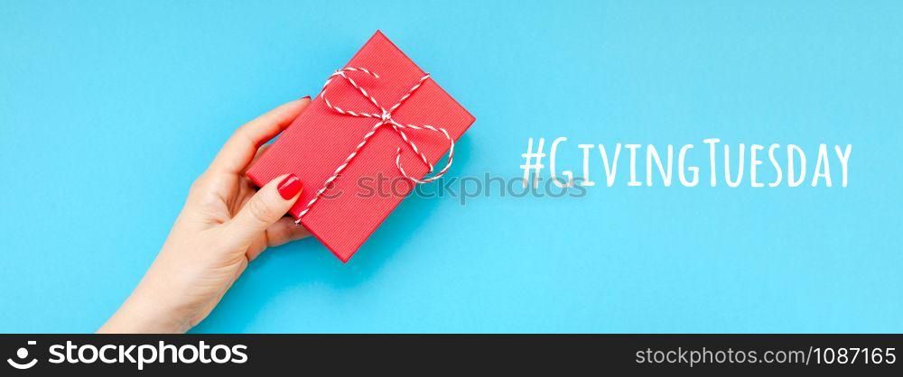 Giving Tuesday is a global day of charitable giving after Black Friday shopping day. Charity, give help, donations and support concept with text message sign and woman hand holding red gift box