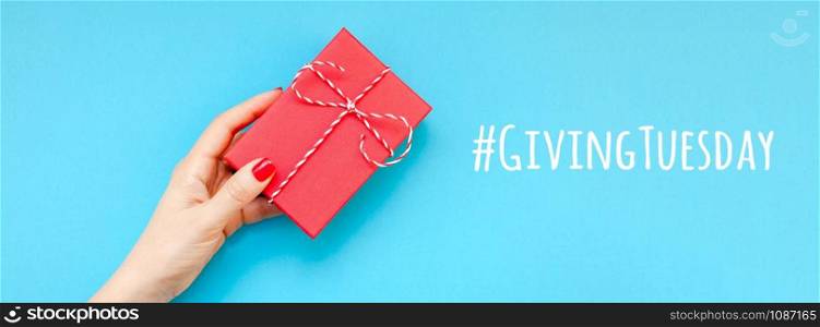 Giving Tuesday is a global day of charitable giving after Black Friday shopping day. Charity, give help, donations and support concept with text message sign and woman hand holding red gift box