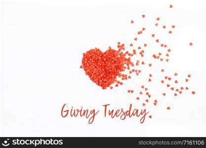 Giving Tuesday is a global day of charitable giving after Black Friday shopping day. Charity, give help, donations and support concept with text message and red heart shaped confetti white background