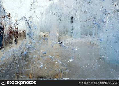 Glacial transparent wall of ice with interesting drawings and patterns and silhouette behind. Closeup, background.