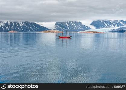 Glacier, mountains and sailing ship in a cloudy day in Svalbard islands, Norway. Glacier, mountains and sailing ship in Svalbard islands