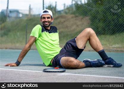 Glad cheerful positive tennis player posing on padel court.