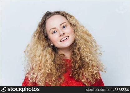 Glad lovely adorable young beautiful woman wth curly hair, dressed casually, expresses positive emotions and feelings being satisfied to have date with boyfriend, isolated over white background