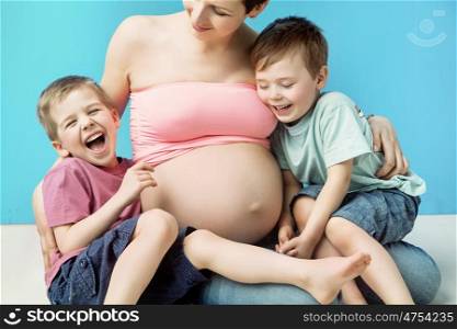 Glad pregnant mother embracing her cute sons