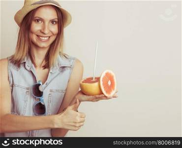 Glad woman in hat with sunglasses and grapefruit. Happy glad woman tourist in straw hat with sunglasses and grapefruit citrus fruit giving thumb up. Healthy diet food. Summer vacation holidays concept.