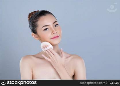 Glamorous beautiful female model applying cushion powder for facial makeup concept. Portrait of flawless perfect cosmetic skin woman put powder puff on her face in isolated background.. Glamorous beautiful female model applying powder puff for facial makeup concept.