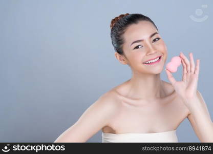 Glamorous beautiful female model applying cushion powder for facial makeup concept. Portrait of flawless perfect cosmetic skin woman put powder puff on her face in isolated background.. Glamorous beautiful female model applying powder puff for facial makeup concept.