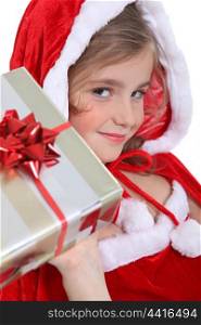 Glamorous child in a Santa&rsquo;s outfit offering a gift