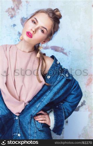 Glamorous girl with bright pink lips wearing rough denim jacket and delicate silk top