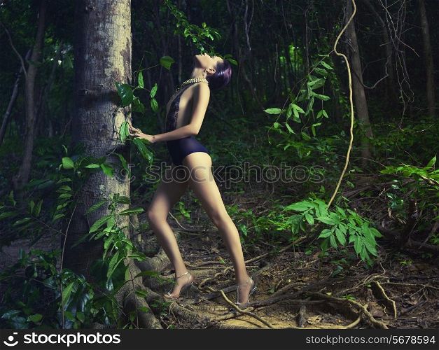 Glamorous lady in a lace leotard in a tropical forest