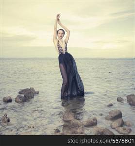Glamorous lady in an gorgeous dress standing in sea