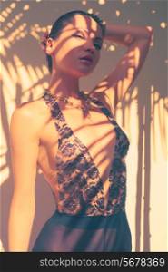 Glamorous lady in lace leotard. Sun rays through the palms