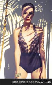 Glamorous lady in lace leotard. Sun rays through the palms