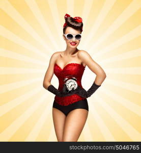 Glamorous pinup girl in a red vintage corset holding a retro alarm clock in her hand and smiling on colorful abstract cartoon style background.