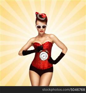 Glamorous pinup girl in a red vintage corset holding a retro alarm clock in her hand and posing on colorful abstract cartoon style background.