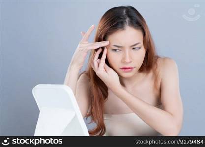 Glamorous portrait of beautiful woman feel insecure on acne spots problem. Worried female model with perfect smooth clean skin checking her face on mirror in isolated background.. Glamorous portrait of beautiful woman feel insecure on her facial skin on mirror