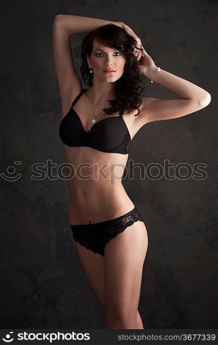 Glamorous sexy standing woman in black lingerie on dark background