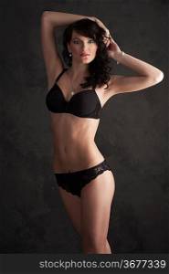 Glamorous sexy standing woman in black lingerie on dark background