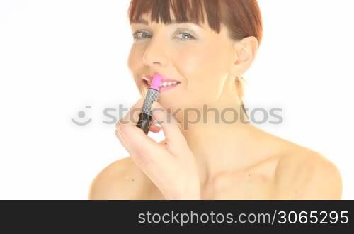 Glamour and beauty portrait of a beautiful woman applying pink lipstick to her lips