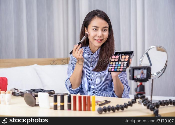Glamour Asian woman beauty blogger or vlogger showing make up with palette and Live on social network media via video or mobile phone, video recording by herself,makeup tutorial,cosmetics vlog concept