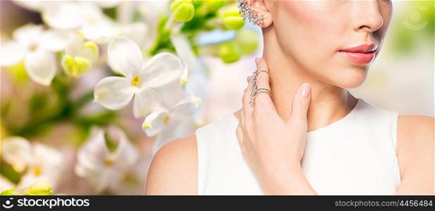 glamour, beauty, jewelry and luxury concept - close up of beautiful woman with golden ring and diamond earring over natural spring lilac blossom background