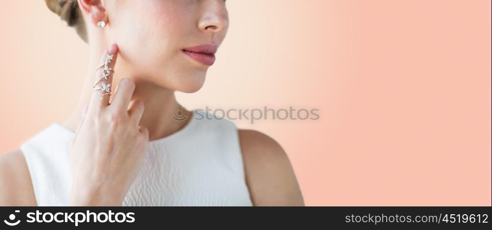 glamour, beauty, jewelry and luxury concept - close up of beautiful woman with golden ring and diamond earringover beige background