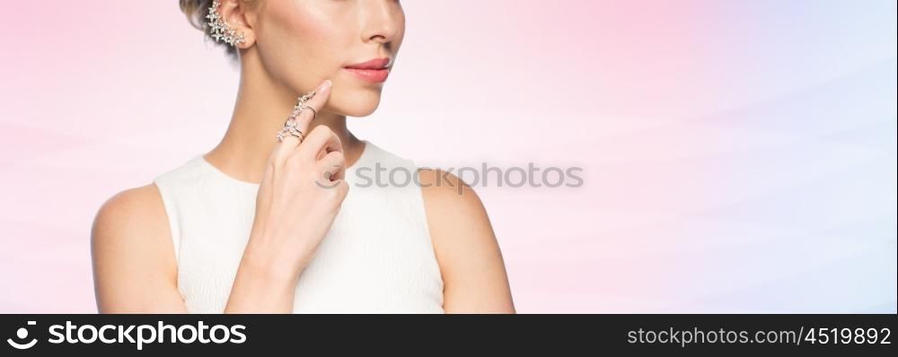 glamour, beauty, jewelry and luxury concept - close up of beautiful woman with golden ring and diamond earring over rose quartz and serenity gradient background