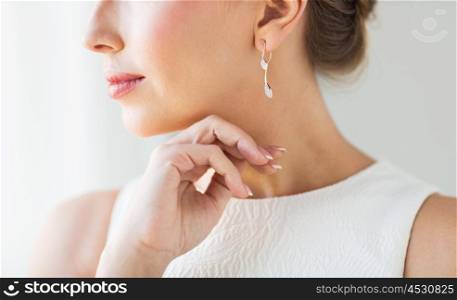 glamour, beauty, jewelry and luxury concept - close up of beautiful woman face with gold and diamond earring