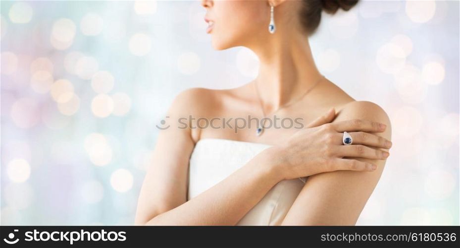 glamour, beauty, jewelry and luxury concept - close up of beautiful woman with finger ring over holidays lights background